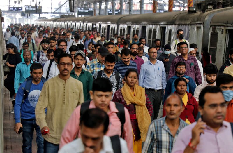 Commuters walk on a platform after disembarking from a suburban train, in Mumbai