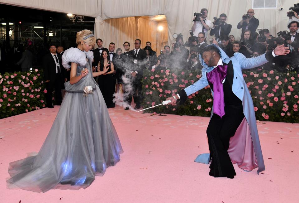 Stylist Law Roach, dressed as the fairy godmother from Cinderella, waves a smoking wand at Zendaya, whose Met Gala dress looks like Cinderella's blue ballgown.