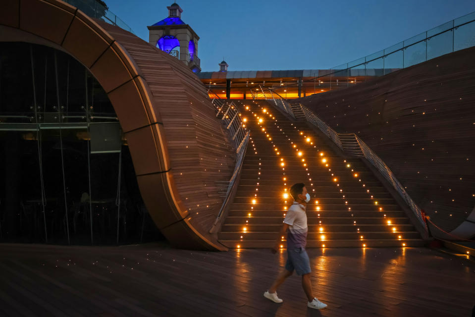A pedestrian wearing a protective face mask walks on a boardwalk in Singapore. 