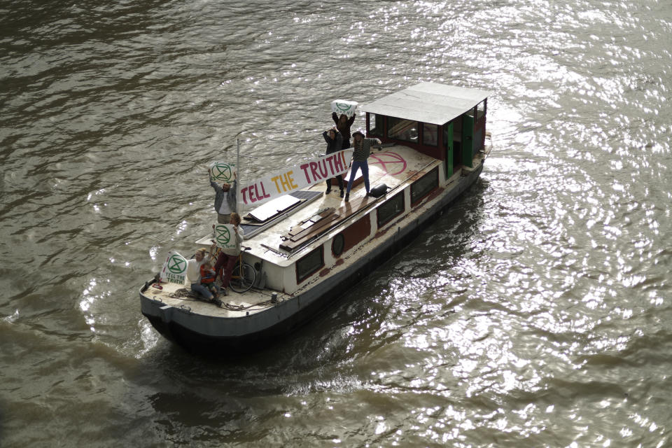 Climate protestors on a boat with a banner reading "Tell the Truth" pass Britain's Parliament in central London Monday, Oct. 7, 2019. Activists with the Extinction Rebellion movement blocked major roads in London, Berlin and Amsterdam on Monday at the beginning of what was billed as a wide-ranging series of protests demanding new climate policies. (AP Photo/Matt Dunham)