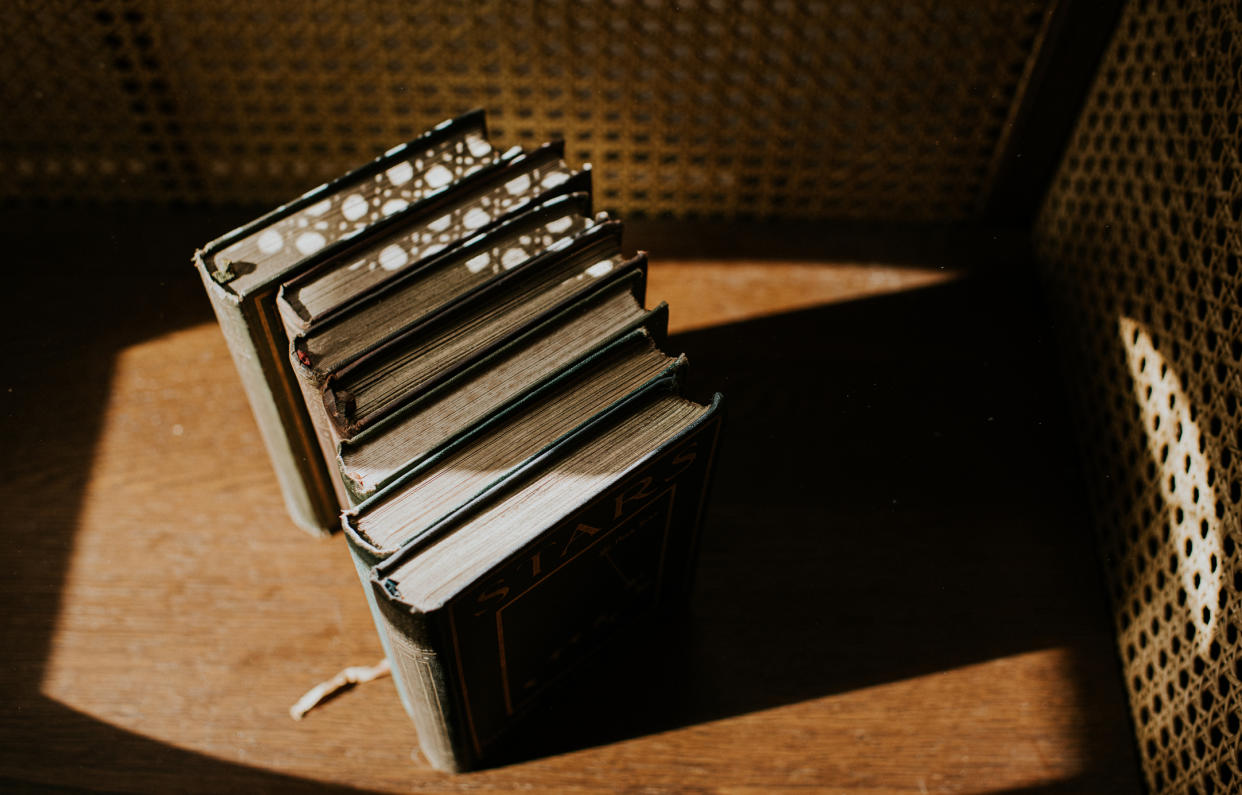  Overhead view of several old books in sunlight on a wooden surface. 