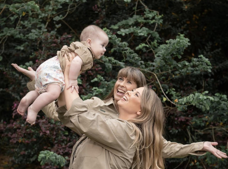 Terri Irwin watches Bindi Irwin Powell as she raises her daughter Grace Warrior Irwin Powell above her head