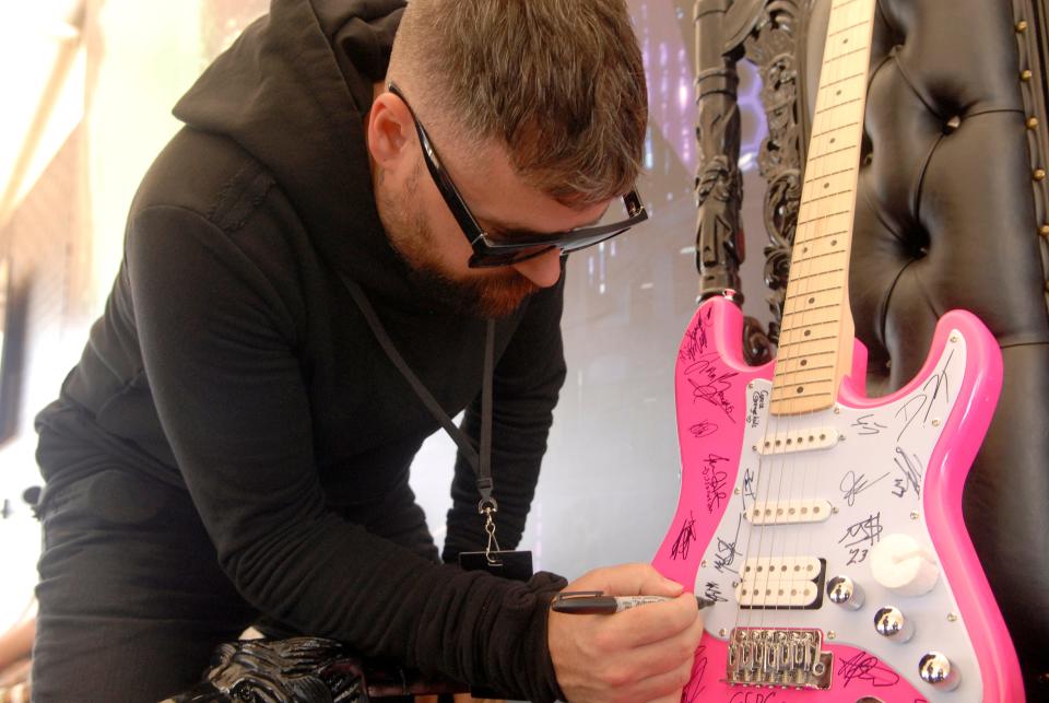 Kyle Therrien, from the band Strange Kids, signs a guitar for the Road Hounds lounge at Louder Than Life on Saturday. Sept. 23, 2023