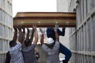 FILE - In this April 13, 2021 file photo, the remains of a woman who died from complications related to COVID-19 are placed into a niche by cemetery workers and relatives at the Inahuma cemetery in Rio de Janeiro, Brazil. As Brazil hurtles toward an official COVID-19 death toll of 500,000, epidemiologists at the University of Sao Paulo say the true toll is closer to 600,000, maybe 800,000. (AP Photo/Silvia Izquierdo, File)