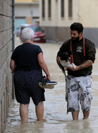 Gente cruzando por una calle inundada cerca del desbordado río Segura mientras las lluvias torrenciales azotan Orihuela, cerca de Murcia, España, el 13 de septiembre de 2019