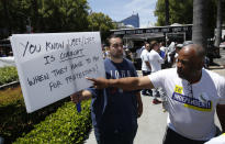 FILE -In this July, 9, 2019, file photo, ride-share driver Pierre Finley, right, a supporter of a measure to limit when companies can label workers as independent contractors, questions Ruben Houghtailing, about his opposition to the bill, during a rally in Sacramento, Calif. California lawmakers are debating a bill that would make companies like Uber and Lyft label their workers as employees, entitling them to minimum wage and benefits. (AP Photo/Rich Pedroncelli, File)