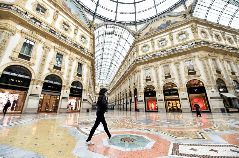 FILE PHOTO: A woman wearing a protective face mask walks in Galleria Vittorio Emanuele II after a decree orders for the whole of Italy to be on lockdown in an unprecedented clampdown aimed at beating the coronavirus, in Milan