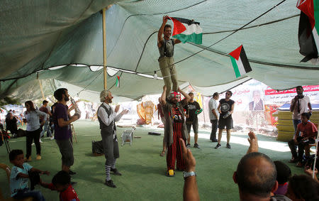 Clowns perform in front of Palestinian children in the Bedouin village of Khan al-Ahmar that Israel plans to demolish, in the occupied West Bank September 22, 2018. REUTERS/Mussa Qawasma