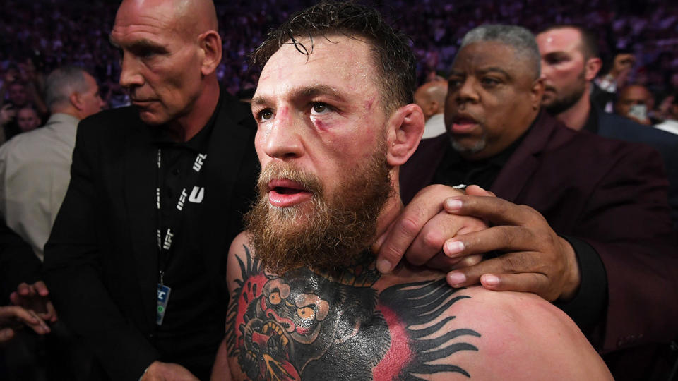 Conor McGregor with a swollen face and being escorted out after a loss.