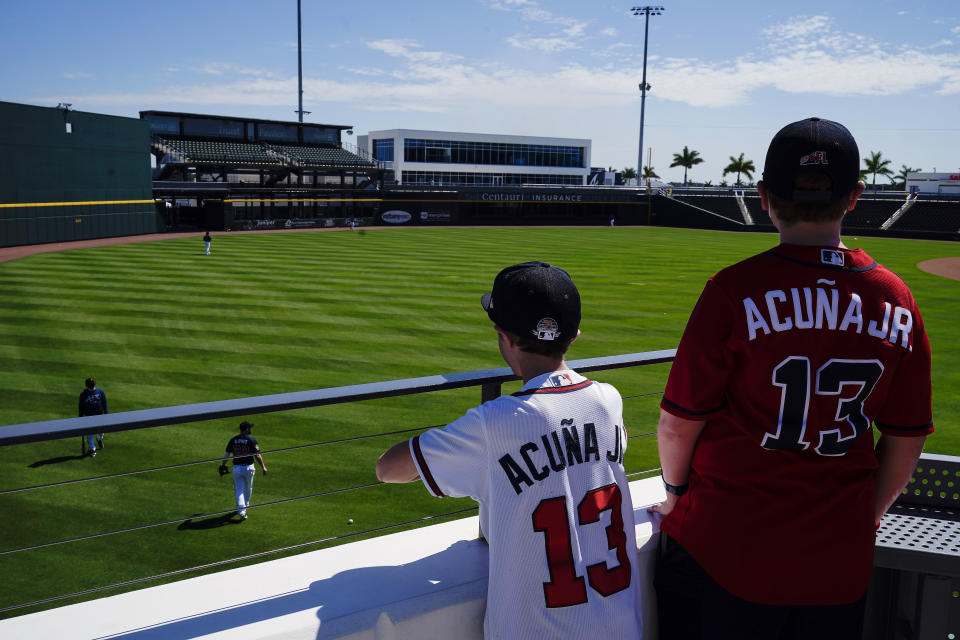 A few fans watch the Atlanta Braves play in the outfield during spring training baseball practice on Tuesday, Feb. 23, 2021, in North Port, Fla. (AP Photo/Brynn Anderson)