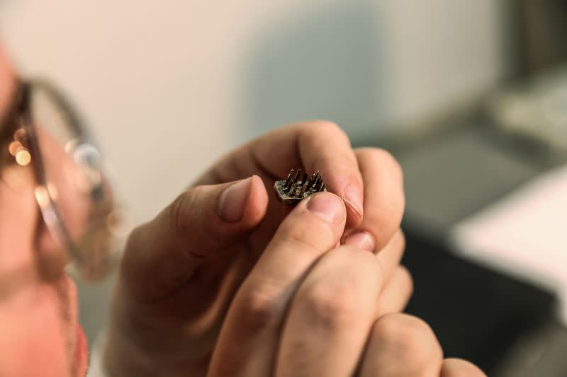 FILE PHOTO: A worker at an Israeli auction house holds a die from a tattoo kit, which they say were used on inmates at Auschwitz death camp, in Gilo