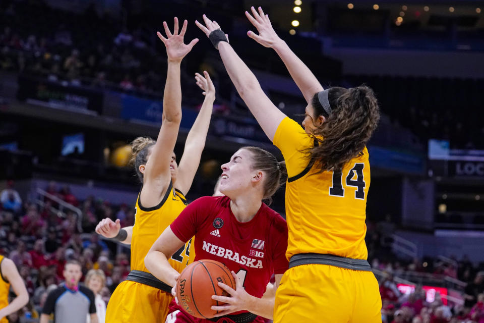 Nebraska forward Isabelle Bourne (34) tries to shoot between Iowa guard Gabbie Marshall (24) and guard McKenna Warnock (14) in the first half of an NCAA college basketball game at the Big Ten Conference tournament in Indianapolis, Saturday, March 5, 2022. (AP Photo/Michael Conroy)