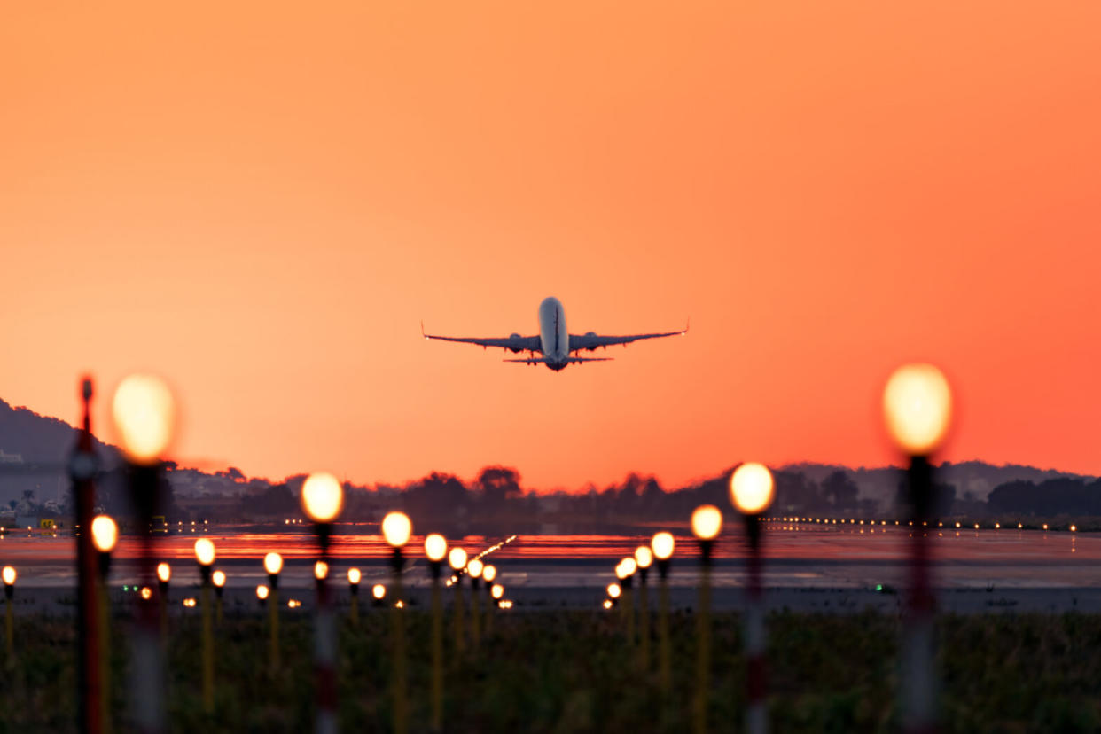 plane taking off runway at sunset