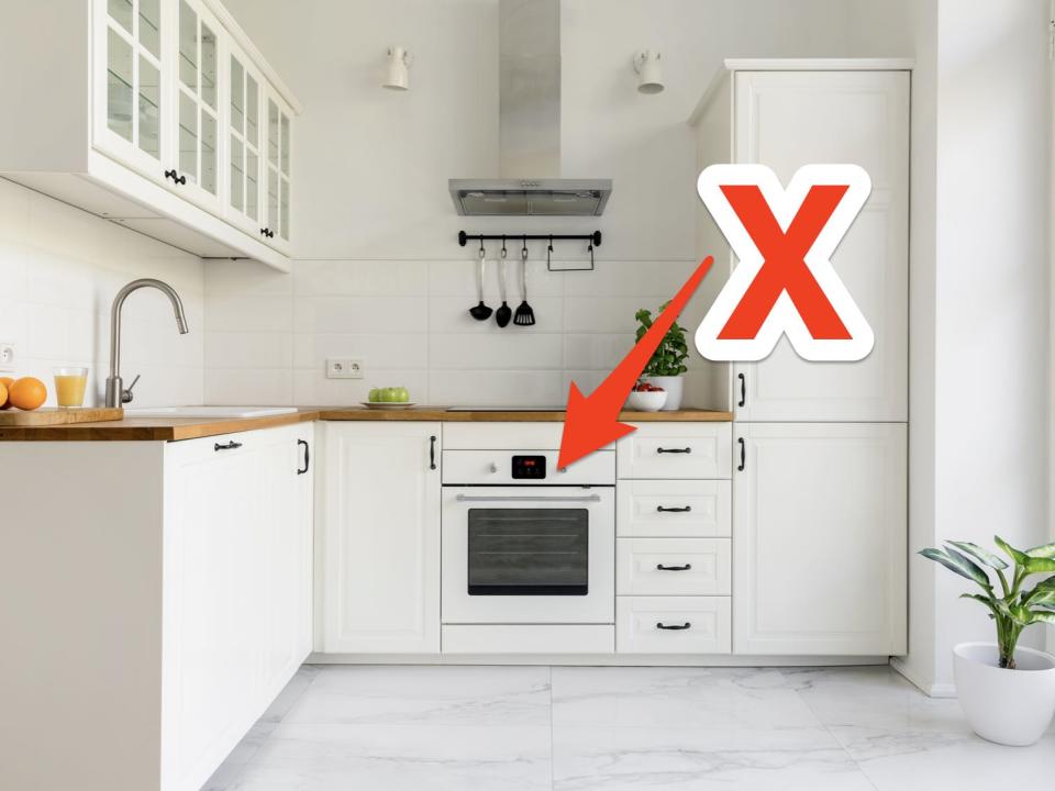 red x and arrow pointing at a white oven in a white minimal kitchen