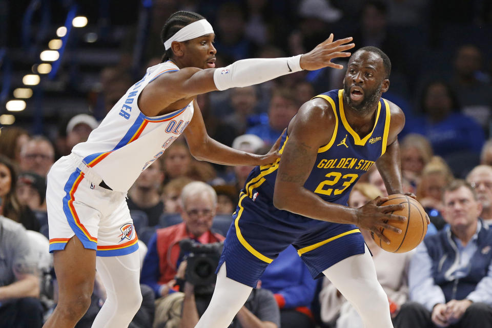 Golden State Warriors forward Draymond Green (23) holds the ball as Oklahoma City Thunder guard Shai Gilgeous-Alexander defends during the first half of an NBA basketball game Friday, Dec. 8, 2023, in Oklahoma City. (AP Photo/Nate Billings)