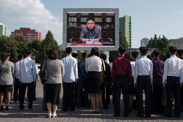 Spectators listen to a television news brodcast of a statment by North Korean leader Kim Jong-Un, before a public television screen outside the central railway station in Pyongyang on September 22, 2017