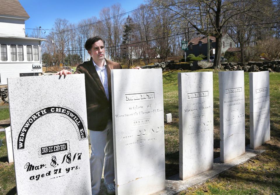 John Herman, author of "Wentworth Cheswill’s Ride," stands solemnly at the Newmarket cemetery, where Wentworth Cheswill, a notable figure in American history, rests alongside his wife and children.
