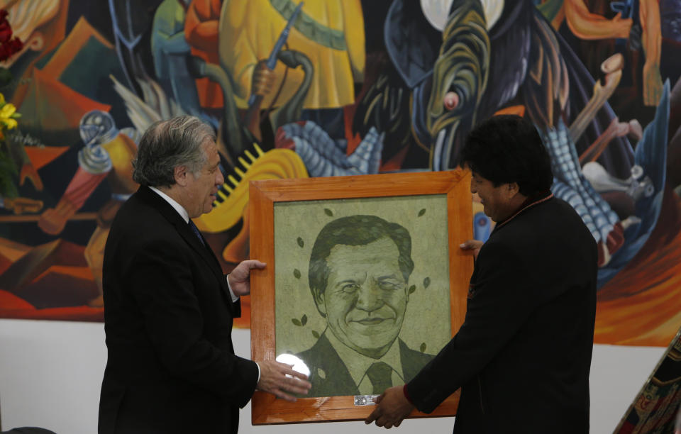 Secretary General of the Organization of American States Luis Almagro, left, receives a portrait of himself designed with painted coca leaves, from Bolivia's President Evo Morales, at the government palace in La Paz, Bolivia, Friday, May 17, 2019. Almagro is in Bolivia on an official visit. (AP Photo/Juan Karita)