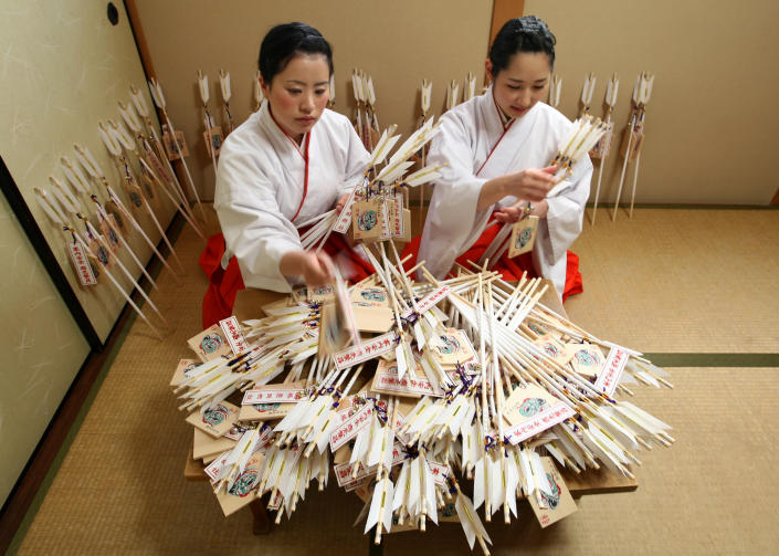 HIMEJI, JAPAN - DECEMBER 27: Mikos (shrine maidens) arrange 'Hamaya' (arrows intended to destroy evil spirits) to which 'Emas' (wooden plaques) are attached featuring a picture of dragon in celebration of the forthcoming 'Year of the Dragon' at Sosha Shrine on December 27, 2011 in Himeji, Japan. Japanese years are commonly associated with the twelve animals Mouse, Cow, Tiger, Rabbit, Dragon, Snake, Horse, Sheep, Monkey, Rooster, Dog and Pig. (Photo by Buddhika Weerasinghe/Getty Images)