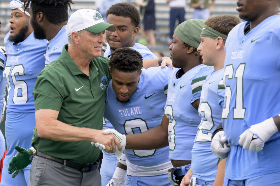 Tulane head coach Willie Fritz hugs running back Iverson Celestine (8) while shaking hands with safety Kam Pedescleaux (8) after the team defeated Tulsa in an NCAA college football game in New Orleans, Saturday, Nov. 11, 2023. (AP Photo/Matthew Hinton)