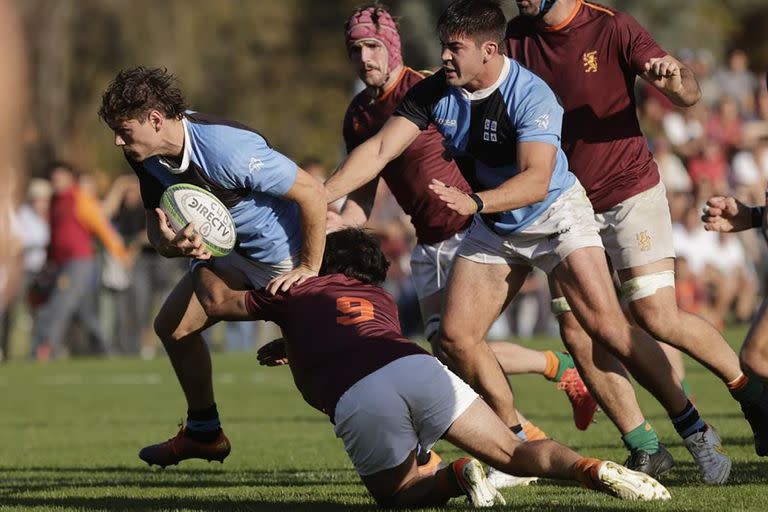 Marcos Young, autor de los primeros dos tries, avanza con la pelota, pese al tackle de Félix Branca; detrás, el apoyo de Pisani