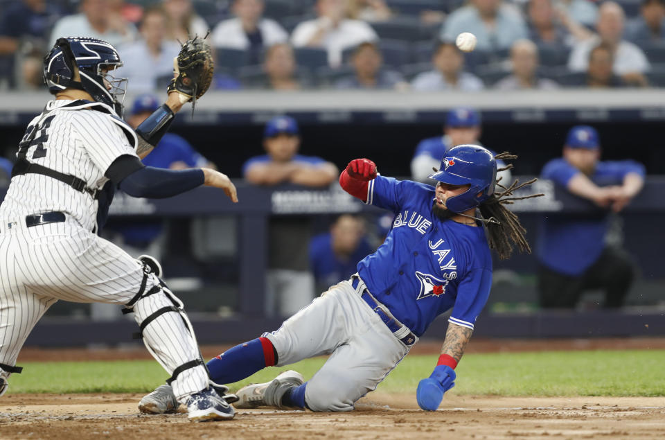 New York Yankees catcher Gary Sanchez, left, waits for the throw as Toronto Blue Jays' Freddy Galvis slides in to score on Eric Sogard's sacrifice fly during the sixth inning of a baseball game Tuesday, June 25, 2019, in New York. (AP Photo/Kathy Willens)