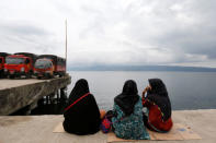 Relatives of the missing passengers from a ferry accident at Lake Toba sit on a pier at Tigaras port in Simalungun, North Sumatra, Indonesia June 21, 2018. REUTERS/Beawiharta