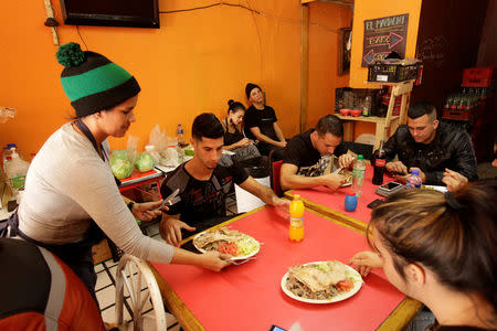 A Cuban migrant, working at a local restaurant while waiting for her appointment to request asylum in the U.S., serves food to fellow nationals, in Ciudad Juarez, Mexico, March 31, 2019. REUTERS/Jose Luis Gonzalez