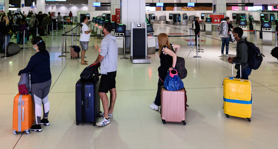 Pictured is a queue of people practising social distancing at Sydney Airport amid coronavirus pandemic. 