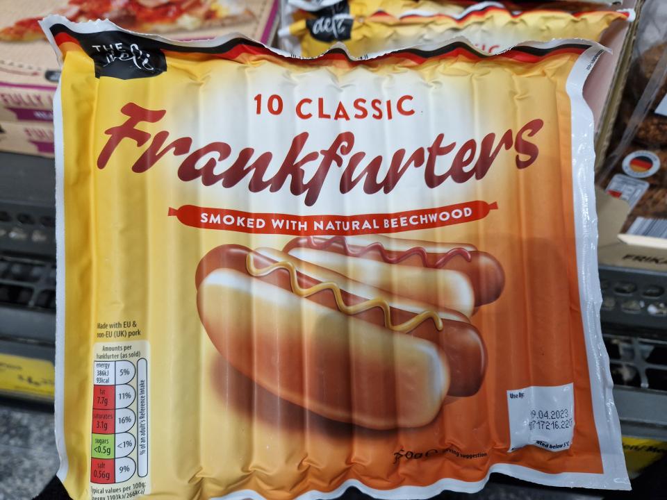 The writer holds a pack of frankfurters