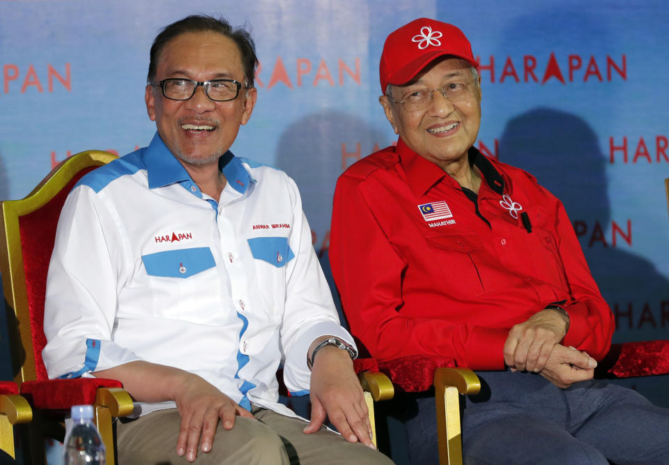 FILE - In this Oct. 8, 2018, file photo, Malaysia's Prime Minister Mahathir Mohamad, right, sits next to Malaysia's reform icon Anwar Ibrahim during a rally in Port Dickson. Political tension is building in Malaysia amid talks that Mahathir will pull his party out of the ruling alliance and team up with opposition parties to form a new government in a major political upheaval. It will thwart his named successor Anwar Ibrahim from taking over. (AP Photo/Vincent Thian)