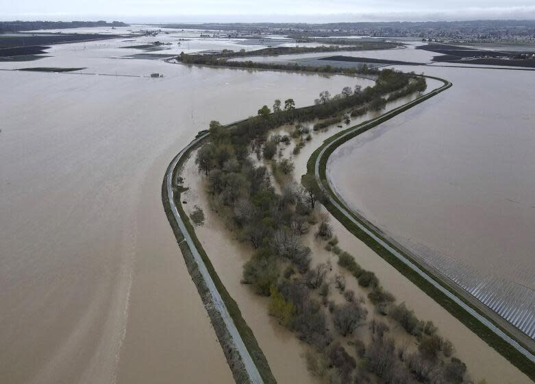 In this aerial photo, the Pajaro River channel snakes along the county line between Monterey County, at left, and Santa Cruz County, Calif., at right, on Sunday, March 12, 2023. Officials had been working to shore up parts of the river's levee system when it was breached around midnight Friday into Saturday. (Shmuel Thaler/The Santa Cruz Sentinel via AP)