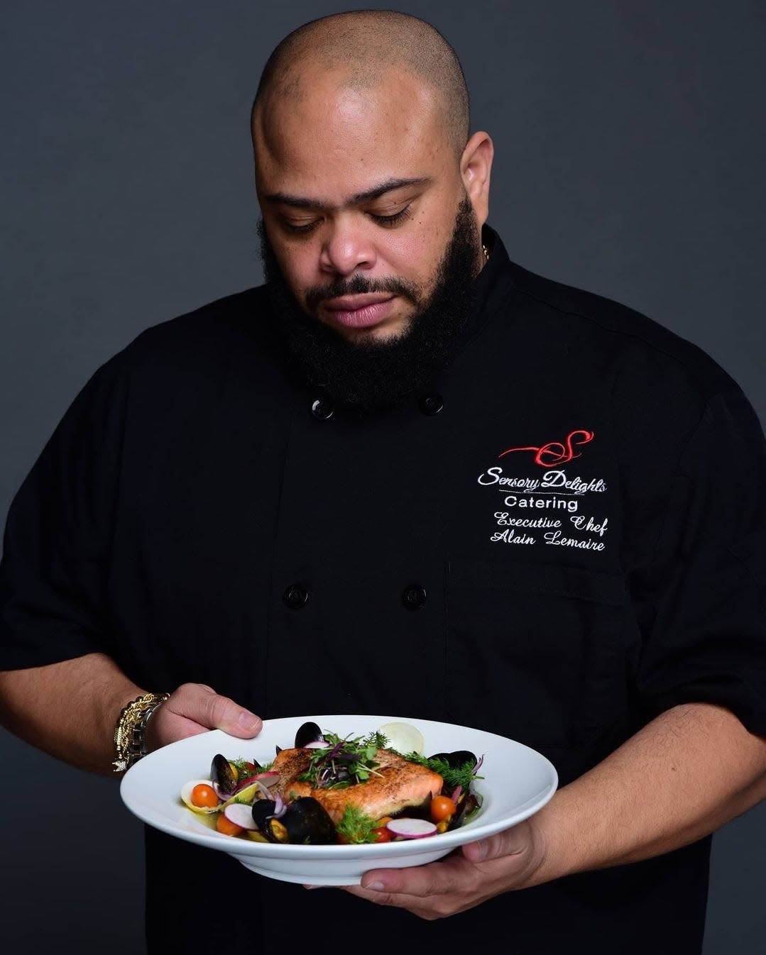 Chef Alain Lemaire holds a plate of salmon, mussels and cherry tomatoes