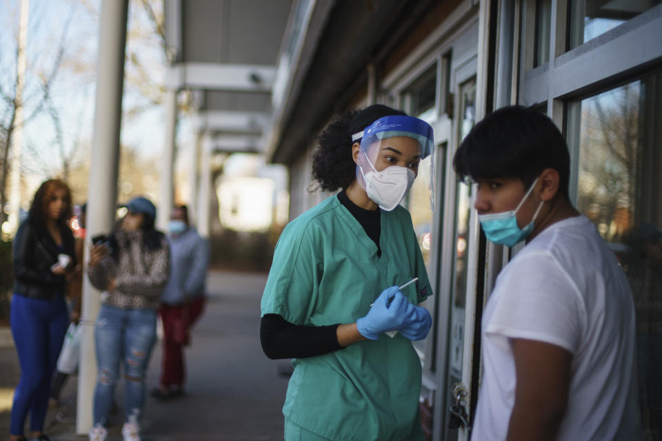 FILE - Maya Goode, a COVID-19 technician, left, talks with Sami Perez, 12, after he received a COVID-19 test outside Asthenis Pharmacy in Providence, R.I., Dec. 7, 2021. The U.S. death toll from COVID-19 topped 800,000, a once-unimaginable figure seen as doubly tragic, given that more than 200,000 of those lives were lost after the vaccine became available practically for the asking. (AP Photo/David Goldman, File)