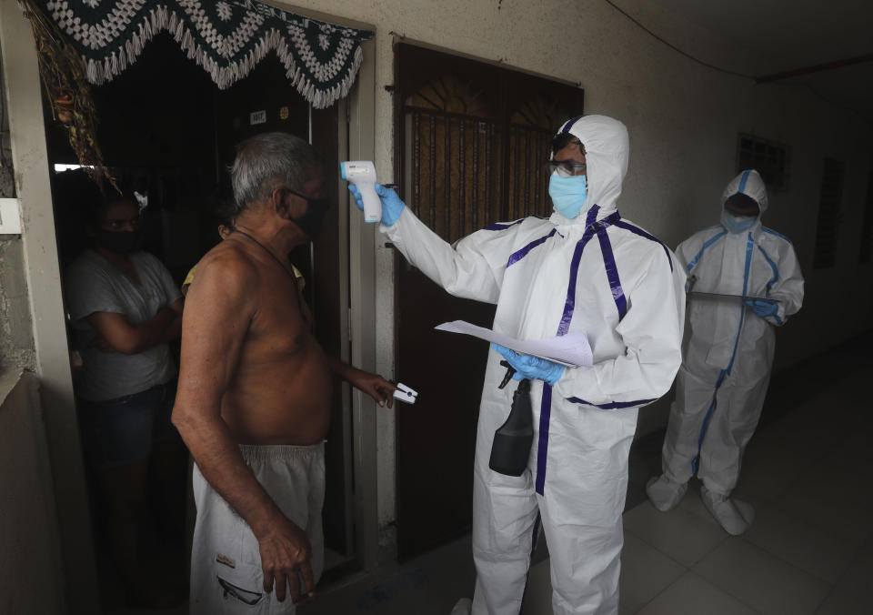 A health worker checks the temperature of a man during a free medical checkup at residential building in Mumbai, India, Thursday, July 2, 2020. Indian Prime Minister Narendra Modi said in a live address Tuesday that the country's coronavirus death rate is under control, but that the country is at a "critical juncture." But since the lockdown was lifted, the caseload has shot up, making India the world's fourth-worst affected country. (AP Photo/Rafiq Maqbool)