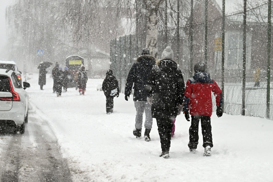 Parents escort their children to the Viertola school in snow-fall in Vantaa, Finland, on Wednesday, April 3, 2024. A 12-year-old student opened fire at a secondary school in southern Finland on Tuesday morning, killing one and seriously wounded two other students, police said. The suspect was later arrested. (Jussi Nukari/Lehtikuva via AP)