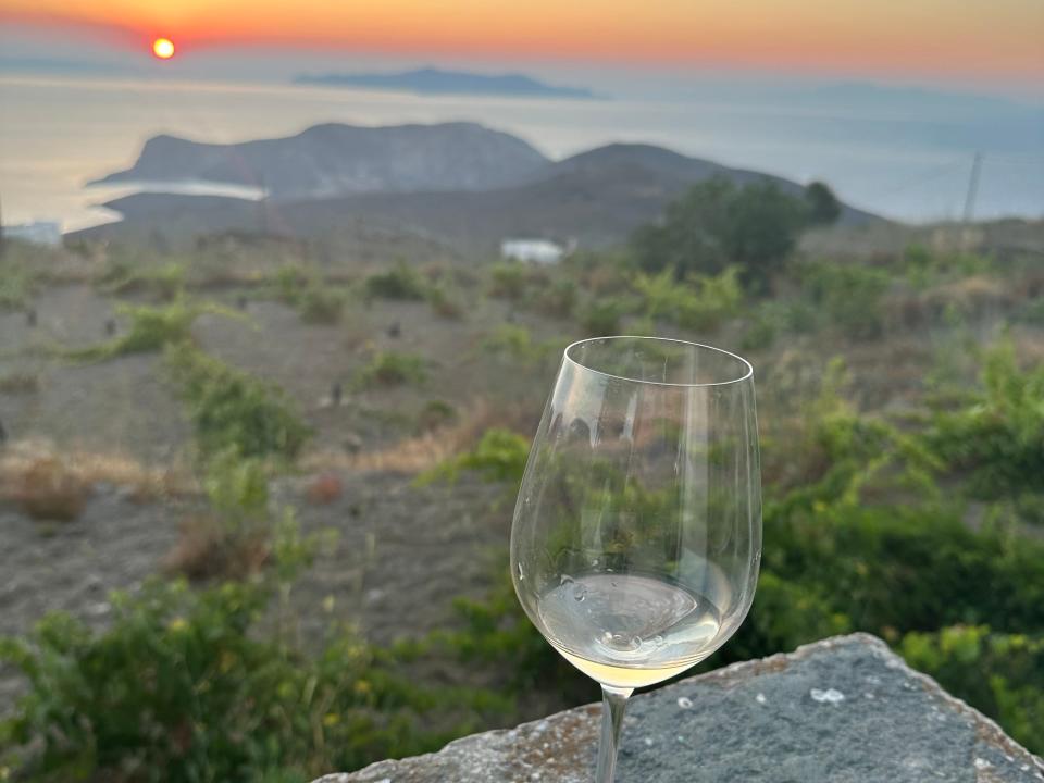 glass of white wine resting on a concrete ledge in a winery in syros greece at sunset