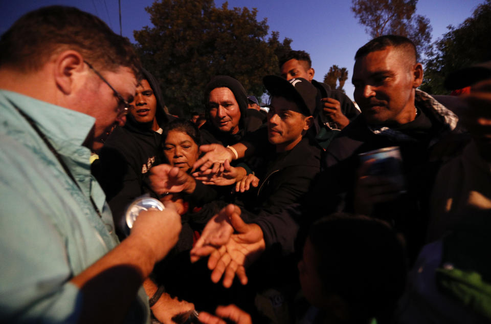 An American well-wisher, left, is swarmed by migrants as he hands out canned soup, adding his efforts to those of many local Mexican groups distributing food outside of a sports complex where more than 5,000 Central Americans are sheltering in Tijuana, Mexico. (Photo: Rebecca Blackwell/ASSOCIATED PRESS)