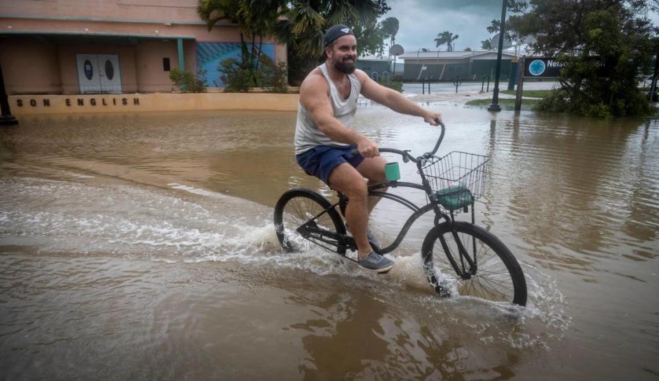 A man rides his bicycle through the floodwaters in front of the Martin Luther King Jr. Memorial Community Center in Key West on Sept. 28, 2022. Hurricane Ian brushed Key West on its way to the mainland, leaving flooded streets due to rain and storm surge.