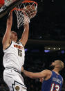 Denver Nuggets center Nikola Jokic (15) dunks the ball over New York Knicks guard Evan Fournier during the first half of an NBA basketball game Saturday, Dec. 4, 2021, in New York. (AP Photo/Adam Hunger)