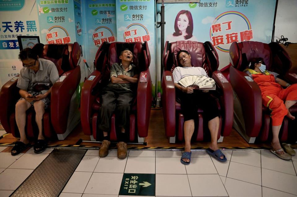 People rest on massage chairs inside a mall as they keep cool and avoid scorching outdoor temperatures in China's southwestern city of Chongqing (Getty Images)