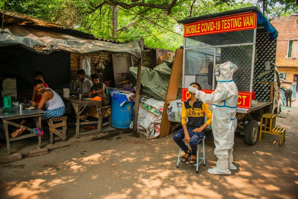 A health worker taking a nasal swab from a man, close to a restaurant. The mobile Covid-19 testing van runs through slum areas conducting rapid antigen tests. It is a free service provided by government to curb the novel coronavirus. (Photo by Pradeep Gaur/SOPA Images/LightRocket via Getty Images)