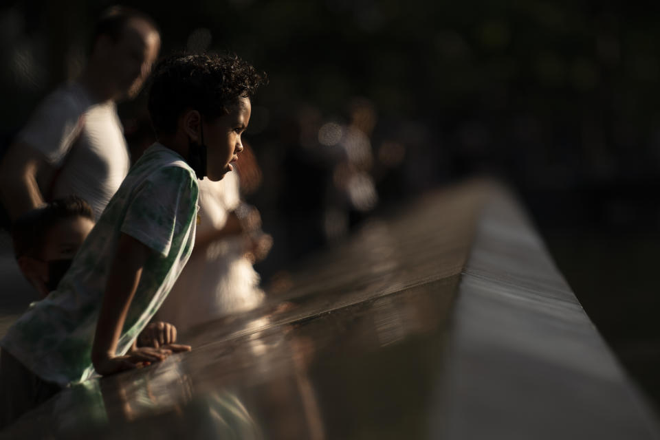 A child peers over the edge of the north pool as visitors browse the walking paths at the National September 11 Memorial & Museum, Wednesday, Sept. 8, 2021, in New York. (AP Photo/John Minchillo)