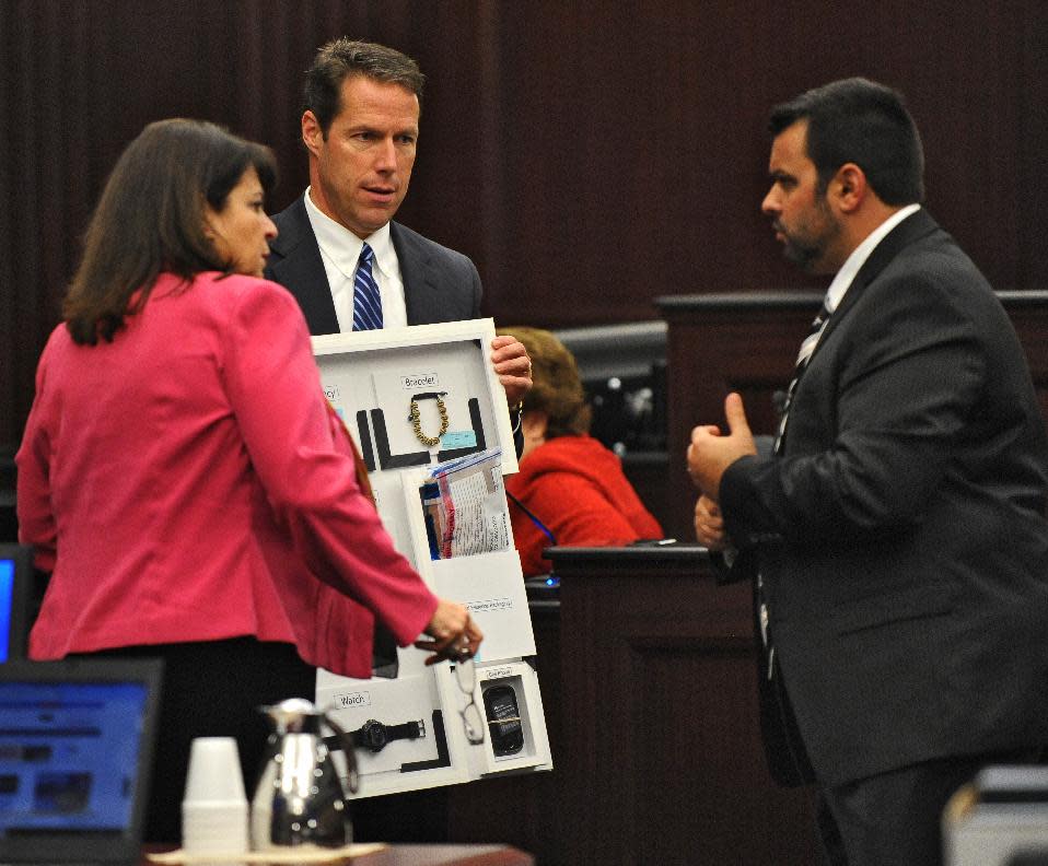 La fiscal estatal Angela Corey (izquierda) habla con Cory Strolla (derecha), el abogado defensor de Michael Dunn, sobre las pertenencias encontradas en los bolsillos de la víctima Jordan Davis, sostenidos por el vicefiscal estatal John Guy (centro). El tercer día del juicio a Michael Dunn por la muerte a tiros de Jordan Davis fue el sábado 8 de febrero de 2014 en Jacksonville, Florida. (Foto AP/The Florida Times-Union, Bob Mack, Pool)