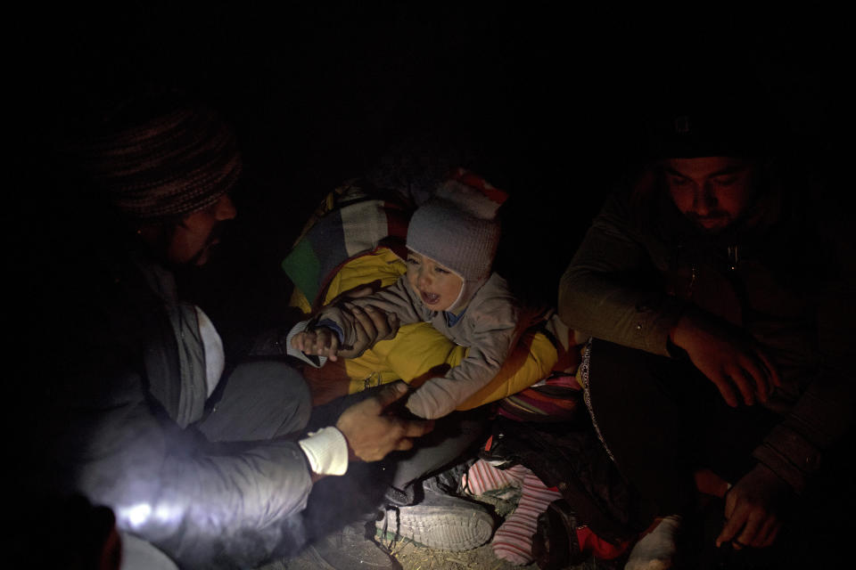In this picture taken Thursday Dec. 12, 2019, Omar, 1, a Syrian refugee from Aleppo, cries while his mother Fatma, 24, tries to change his diaper before continuing their way as they attempt to enter the EU through Croatia in the mountains surrounding the town of Bihac, northwestern Bosnia. (AP Photo/Manu Brabo)