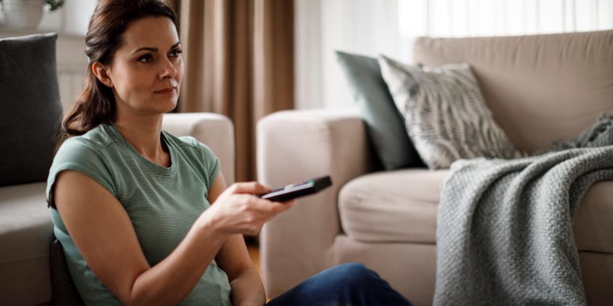 woman at home watching tv with remote control