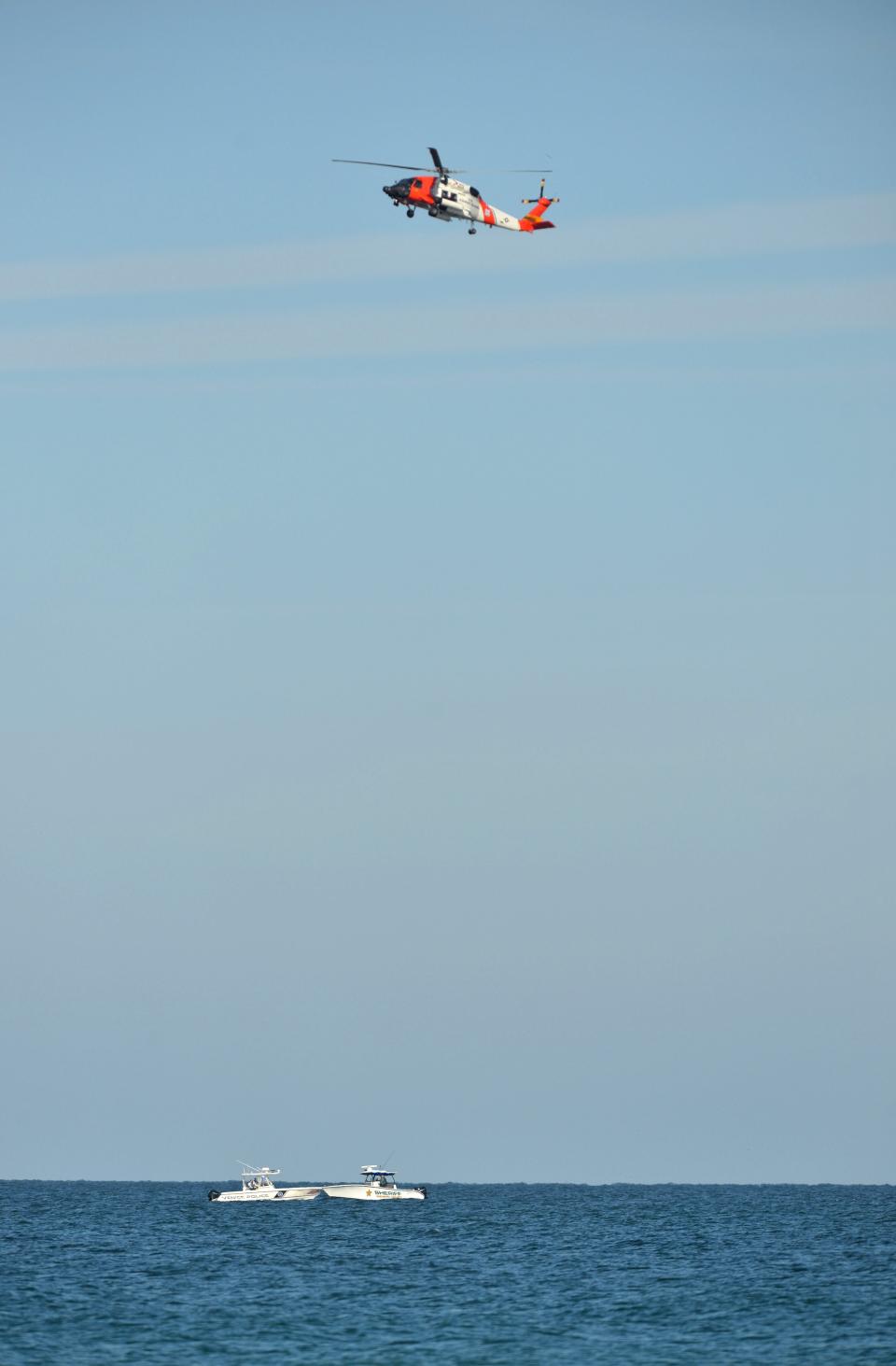 A U.S. Coast Guard helicopter hovers over two law enforcement boats near the Venice Fishing Pier Thursday morning as emergency crews search a debris field in the Gulf of Mexico after a small airplane crash Wednesday night. The bodies of four people have been recovered. 