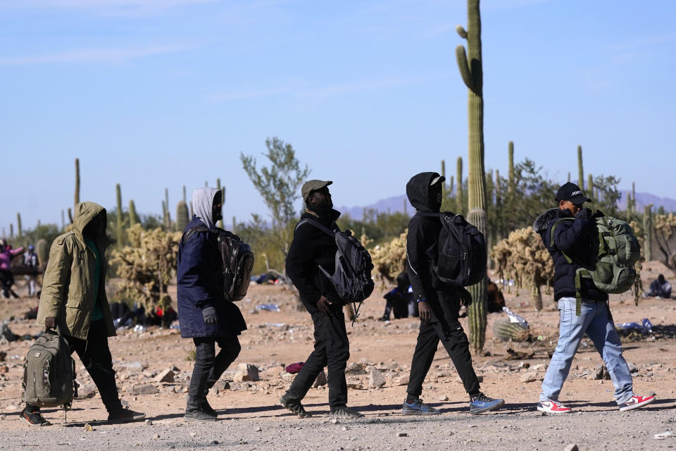FILE - A group of migrants walk to a van as hundreds of migrants gather along the border Tuesday, Dec. 5, 2023, in Lukeville, Ariz. Republicans in swing state Arizona are doubling down on border security with legislation aimed at punishing migrants who enter the United States illegally, including one bill to lawfully allow property owners to shoot and kill anyone criminally trespassing on their property. Democratic Gov. Katie Hobbs is expected to veto both pieces of proposed legislation. AP Photo/Ross D. Franklin, File)