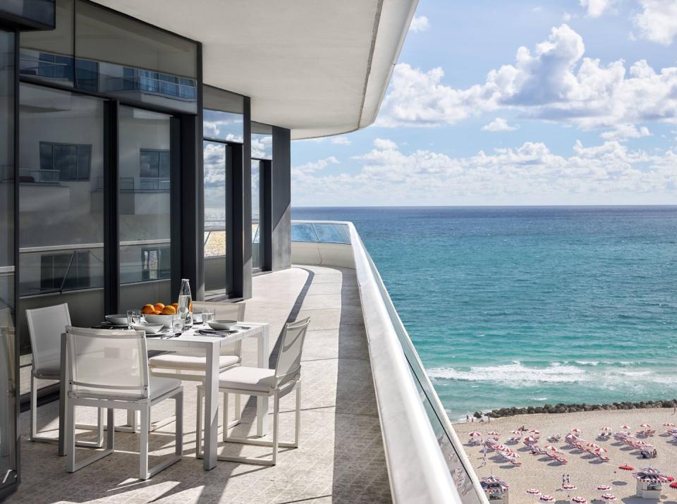 a patio with a table and chairs by the water