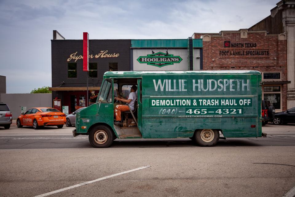 The words "Willie Hudspeth Demolition and Trash Haul Off" are painted on the side of a green truck.